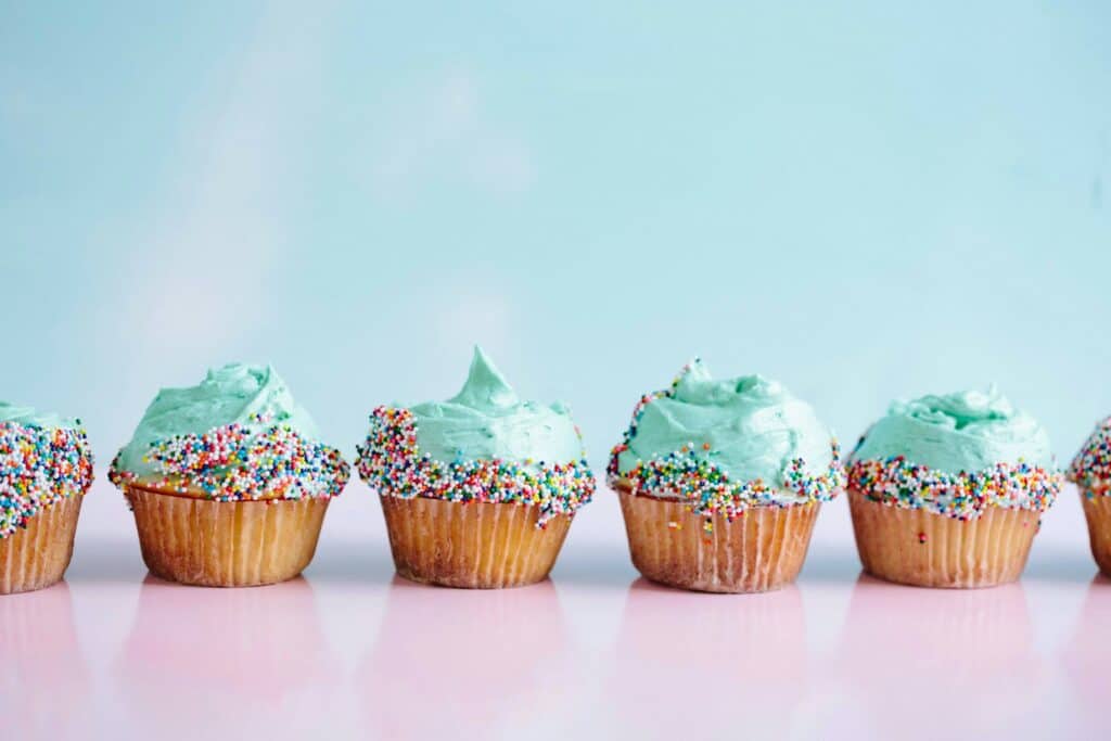 six banting friendly teal icing cupcakes with sprinkles