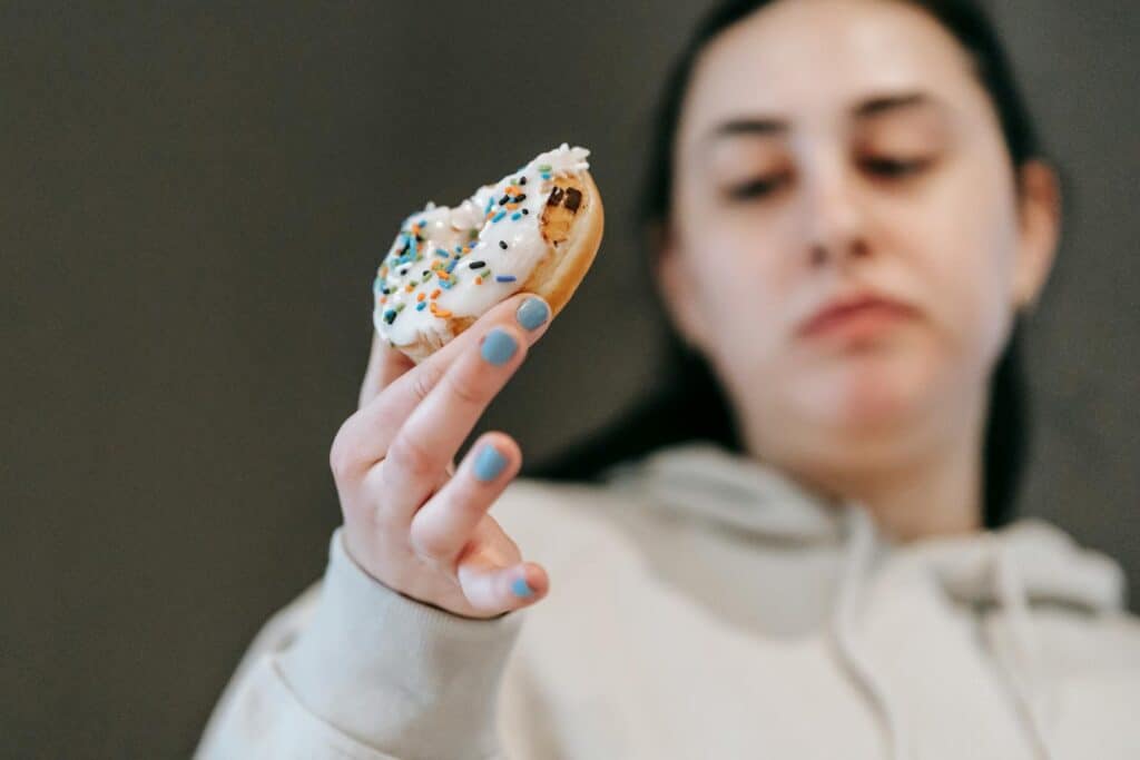 Woman holding a donut, contemplating food choices in moments of stress