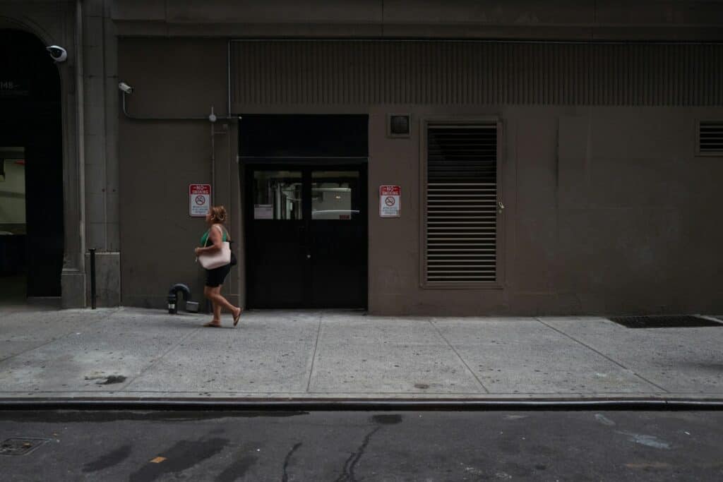 A woman walking down a sidewalk next to a building